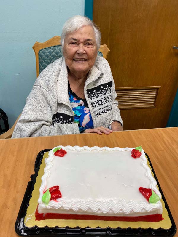 A client smiles behind a birthday cake.