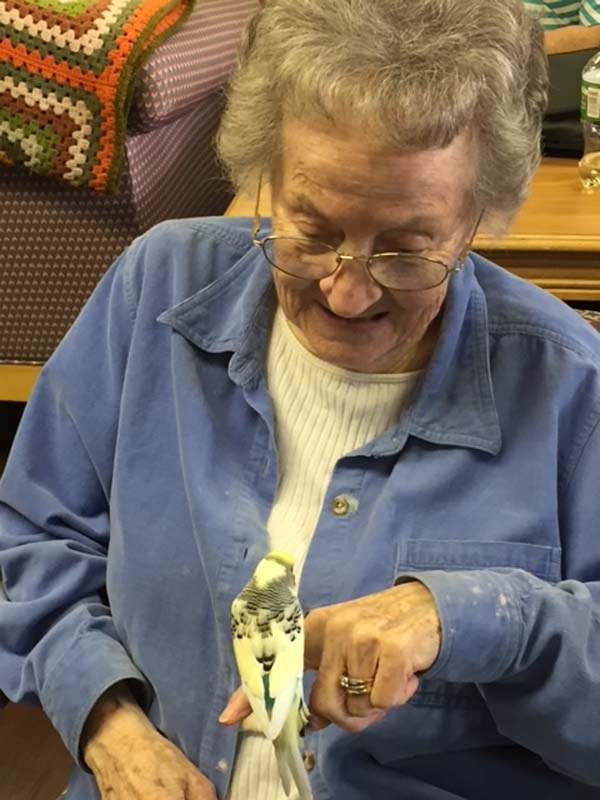 Betty observes a bird perched on her finger.