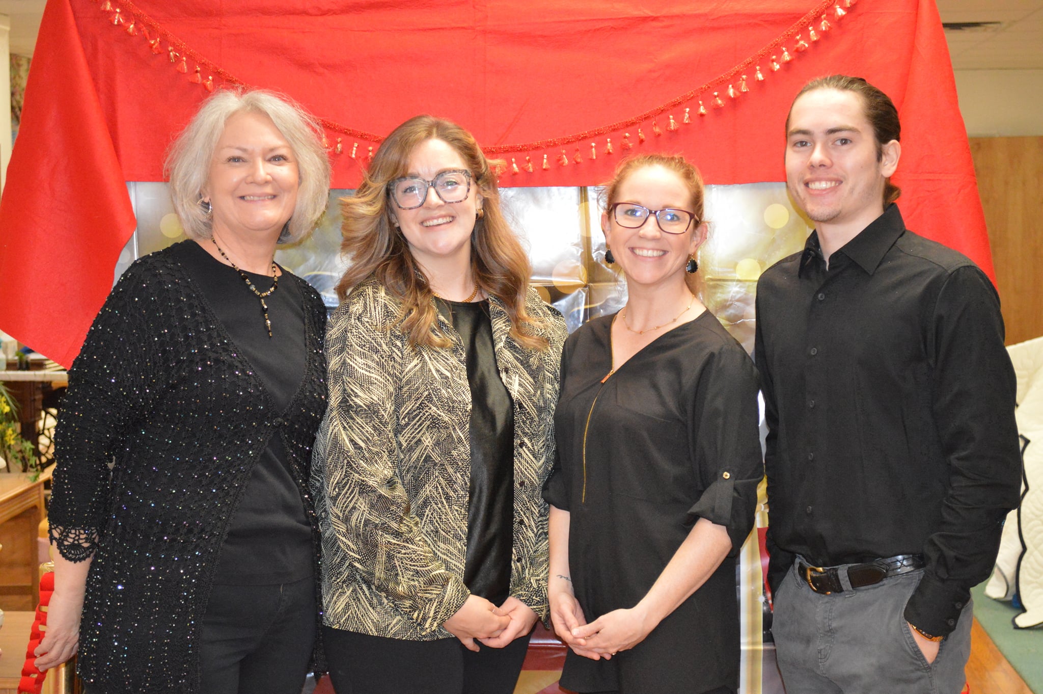 The staff of Nac Treatment Center pose for a photo in front of a red backdrop.